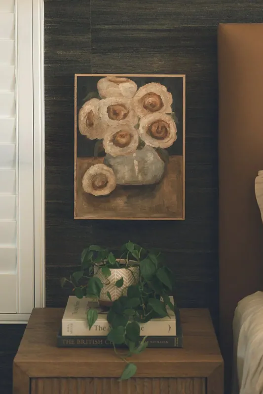 Moody dark wall with a framed floral still life above a console styled with greenery.