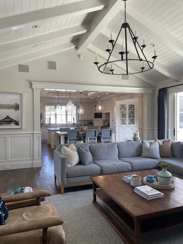 Vaulted family room with a lantern chandelier, a gray sectional, and a leather ottoman coffee table.